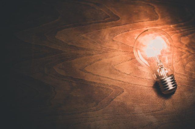 Innovation mangement, lampadina accesa su piano di legno